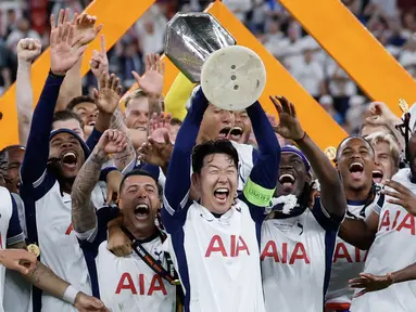Son Heung-min (tengah) mengangkat trofi bersama para pemain Tottenham setelah menjuarai final Liga Europa 2024/2025 di Stadion San Mames, Bilbao, Spanyol, Kamis (22/05/2025) WIB. Tottenham menang dengan skor 1-0 atas Manchester United. (AFP/Thomas Coex)