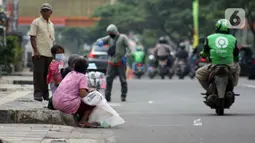 Pemulung duduk duduk di trotoar Jalan Margonda Raya, Depok, Kamis (16/4/2020). Pandemi COVID-19 memberikan dampak yang sangat besar bagi sosial dan ekonomi Indonesia. Bahkan yang paling dikhawatirkan bertambahnya angka kemiskinan dan pengangguran. (Liputan6.com/Helmi Fithriansyah)