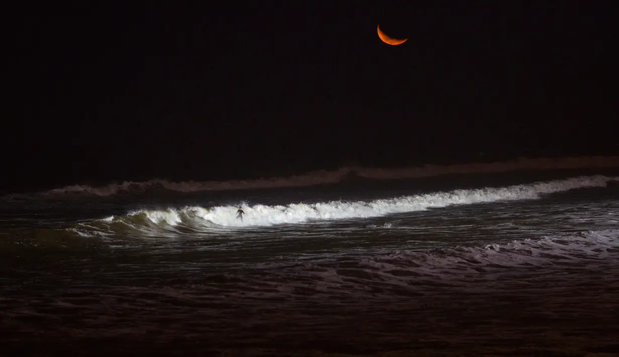 Seorang wisatawan meluncur ke dalam gulungan ombak saat berselancar di pantai La Pampilla, ibu kota Peru, Lima, 2 Maret 2017. Sekelompok peselancar hardcore memilih bermain selancar pada malam hari. (AP Photo/Rodrigo Abd)