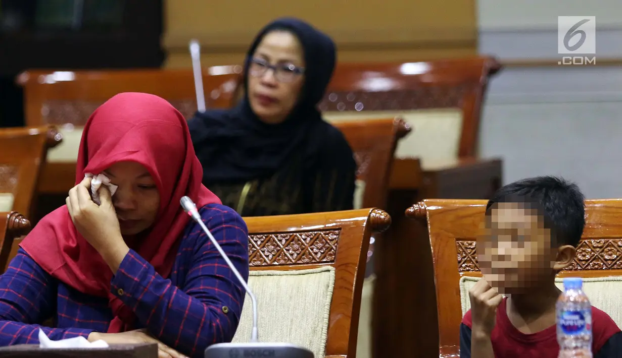 Terpidana kasus pelanggaran UU ITE sekaligus korban pelecehan seksual Baiq Nuril (kiri) menangis saat hadir dalam rapat pleno Komisi III DPR di Gedung Nusantara III, Jakarta, Rabu (23/7/2019). Ibu tiga anak ini tak mau menyerah dan yakin suatu saat keadilan berpihak padanya.(Liputan6.com/JohanTallo)
