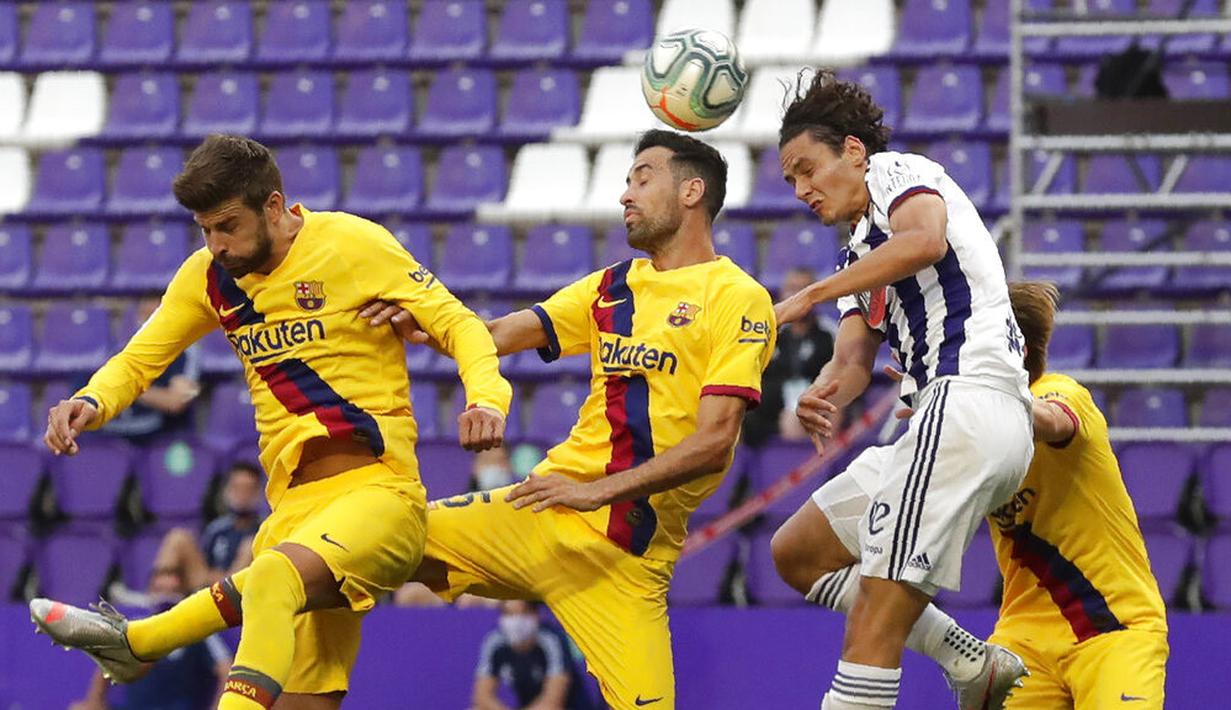 Gelandang Barcelona, Sergio Busquets, duel udara dengan pemain Real Valladolid, Enes Unal, pada laga La Liga di Stadion Jose Zorrilla, Sabtu (11/7/2020). Barcelona menang 1-0 atas Real Valladolid. (AP Photo/Manu Fernandez)