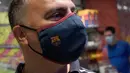 Fans memakai masker berlogo Barcelona di Toko Asesoris Barcelona, Senin (25/5/2020). Di tengah pandemi virus Corona, Barcelona menjual masker dengan harga 18 euro atau sekitar Rp 291 ribu. (AFP/Lluis Gene)