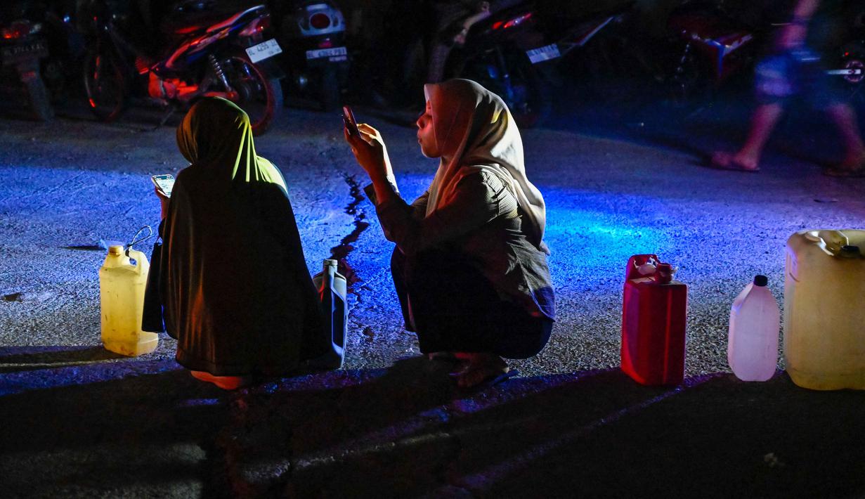 Kelangkaan BBM di Aceh meluas hingga ke tingkat pedagang eceran, di mana sejumlah mesin pompa Pertamini di sepanjang jalanan utama juga telah dimatikan, pada Senin (1/12/2025). Tampak dalam foto, warga terdampak banjir mengantre untuk mendapatkan bahan bakar di sebuah Stasiun Pengisian Bahan Bakar Umum (SPBU) di Samahani, Provinsi Aceh, pada 2 Desember 2025. (CHAIDEER MAHYUDDIN/AFP)