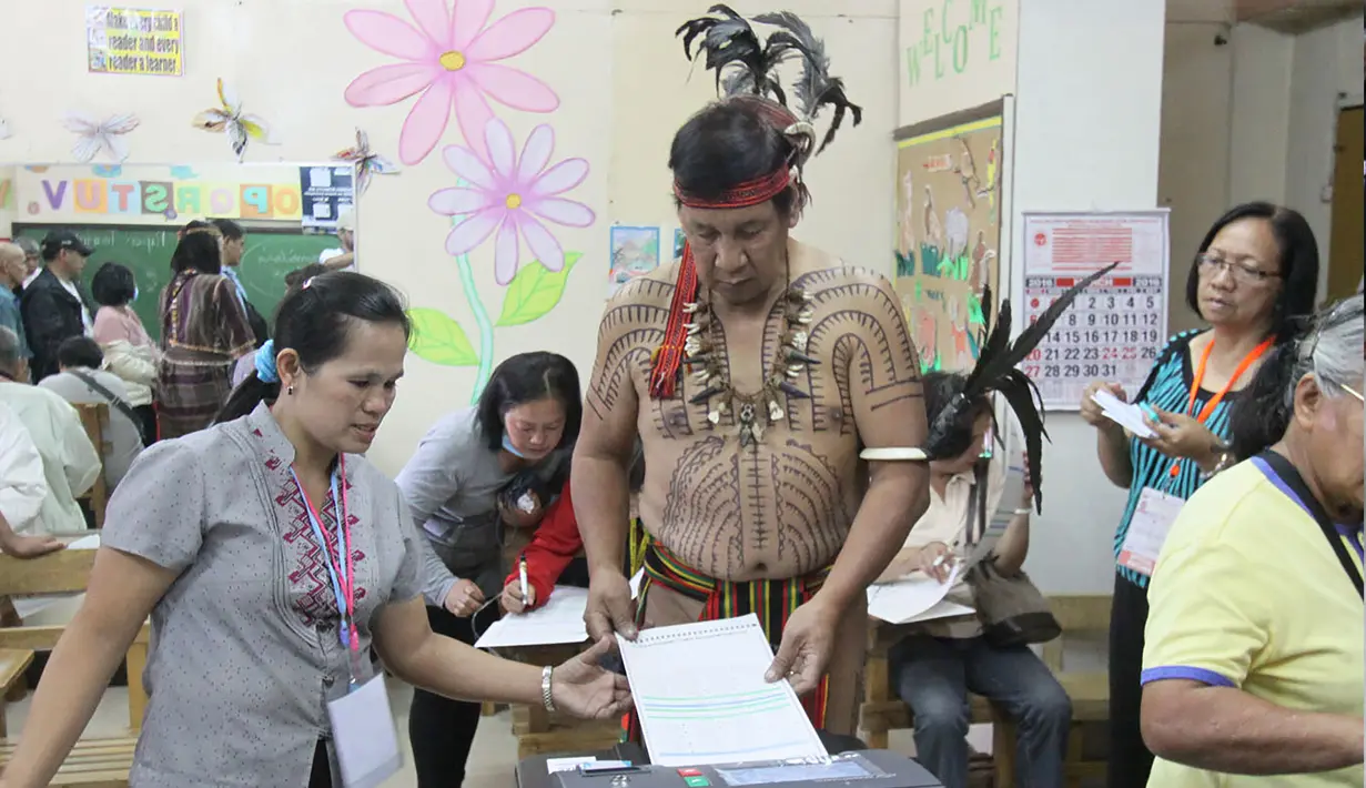 Kepala suku Igorot, Nicolas Cawed dibantu petugas mengambil kertas suara dalam pemilihan presiden di sebuah TPS di Baguio City, Manila Utara, Senin (9/5). Sekitar 50 juta warga Filipina mengikuti pemilihan Presiden. (AFP PHOTO/JJ LANDINGIN)