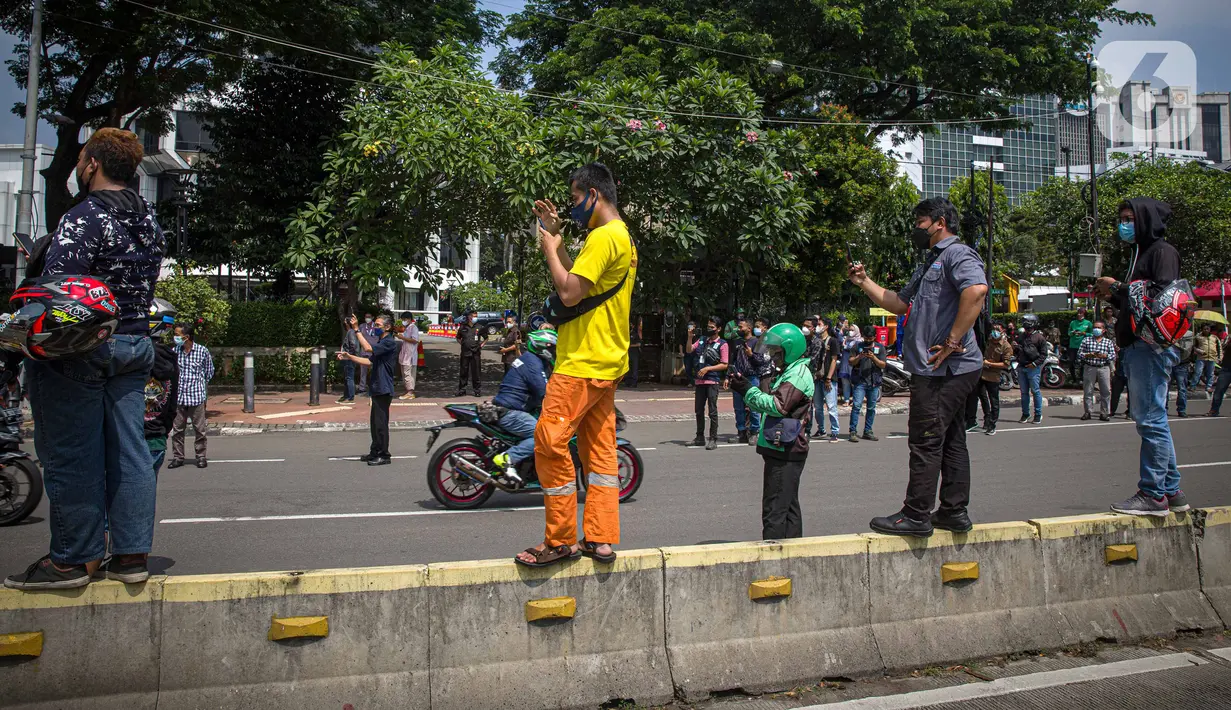Antusias warga menyaksikan parade pembalap MotoGP di kawasan Jakarta, Rabu (16/3/2022).  Sebanyak 20 pembalap MotoGP menjajal ruas Jalan Sudirman-Thamrin, Jakarta Pusat hari ini. (Liputan6.com/Faizal Fanani)