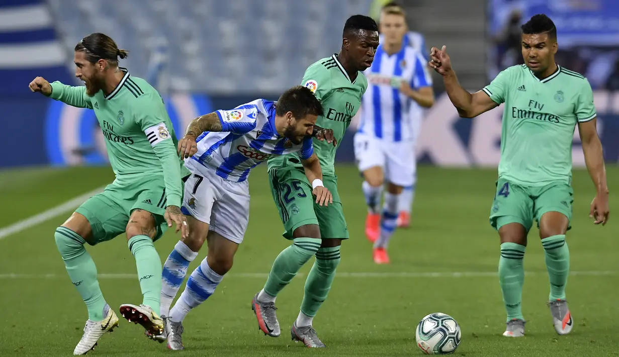 Pemain Real Sociedad Portu berebut bola dengan pemain Real Madrid Vinicius Junior dan Sergio Ramos pada pertandingan La Liga di Stadion Anoeta, San Sebastian, Spanyol, Minggu (21/6/2020). Real Madrid memuncaki klasemen sementara La Liga usai mengalahkan Real Sociedad. (AP Photo/Alvaro Barrientos)