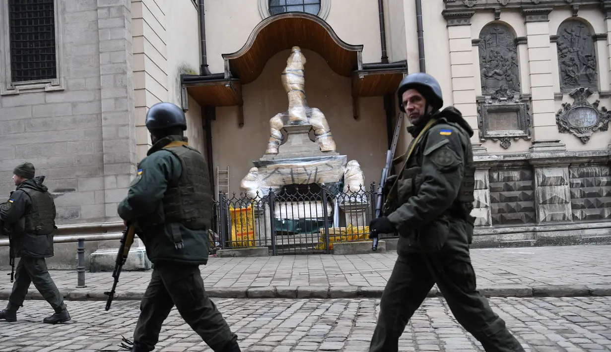 Prajurit Ukraina berjalan melewati patung-patung yang dibungkus di Katedral Latin di Lviv, 5 Maret 2022. Di tengah meningkatnya konflik antara Rusia dan Ukraina, warga kota Lviv membungkus semua patung di kota itu untuk melindungi warisan sejarahnya dari kemungkinan serangan. (Daniel LEAL/AFP)