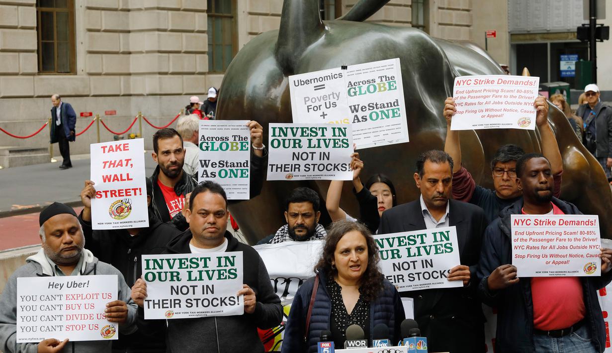 Sopir taksi online Uber menggelar protes di sebelah patung Charging Bull di distrik keuangan New York, AS, Rabu (8/5/2019). Para sopir menuntut kenaikan tarif per kilometer dan dikuranginya komisi yang harus dibayar kepada Uber. (AP Photo/Mark Lennihan)
