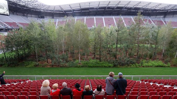 Pengunjung melihat instalasi ekosistem hutan di Stadion Woerthersee, Austria, Minggu (8/9/2019). Lebih dari 300 pohon berbagai jenis , mulai dari pohon aspen, ek, betula, hingga larix ditancapkan dalam karya seni yang berjudul 