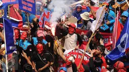 Massa buruh menyalakan suar saat aksi perayaan MayDay di Jalan Medan Merdeka Barat, Senin (5/1). Ribuan massa buruh turun ke jalan dalam perayaan Hari Buruh Internasional. (Liputan6.com/Helmi Fithriansyah)