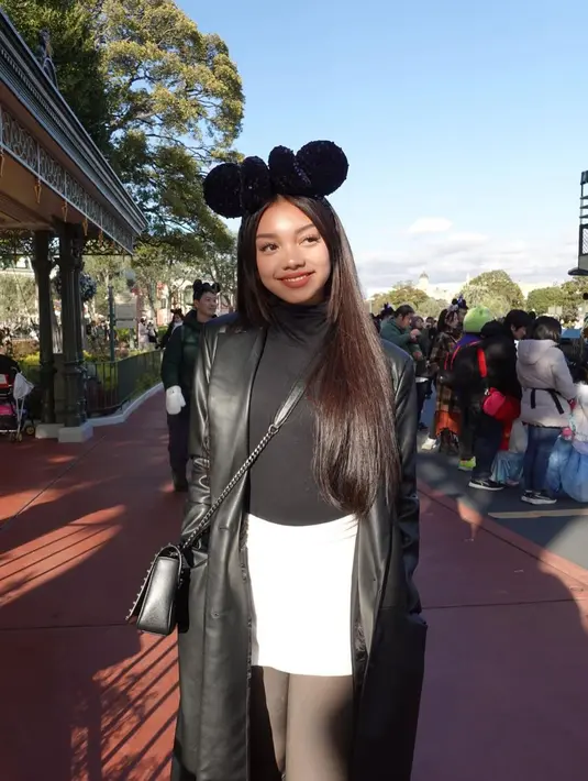 Gaya cantik Naura Ayu ketika liburan. Ia mengenakan turtleneck hitam dipadu mini skirt putih dengan stoking hitam, dan long coat dari bahan kulit yang juga berwarna hitam. [Foto: Instagram/naura.ayu]