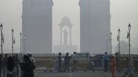 Pejalan kaki berjalan di sepanjang jalan dekat Gerbang India di tengah kabut asap tebal di New Delhi, Kamis (3/11/2022). Setiap musim dingin, udara dingin beserta asap dari petani yang membakar jerami dan emisi kendaraan juga sumber-sumber lainnya bercampur menciptakan kabut asap mematikan. (Money SHARMA / AFP)