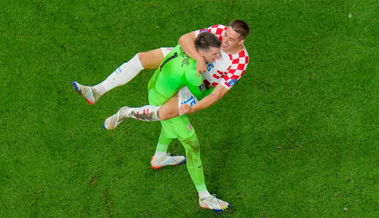 Pemain Kroasia Mario Pasalic merayakan dengan kiper Kroasia Dominik Livakovic setelah mencetak penalti terakhir saat melawan Jepang pada pertandingan sepak bola babak 16 besar Piala Dunia 2022 di Stadion Al Janoub, Al Wakrah, Qatar, 5 Desember 2022. Jepang gagal memecahkan rekor menembus perempat final Piala Dunia 2022 usai disingkirkan Kroasia lewat adu penalti 1-3. (AP Photo/Hassan Ammar)