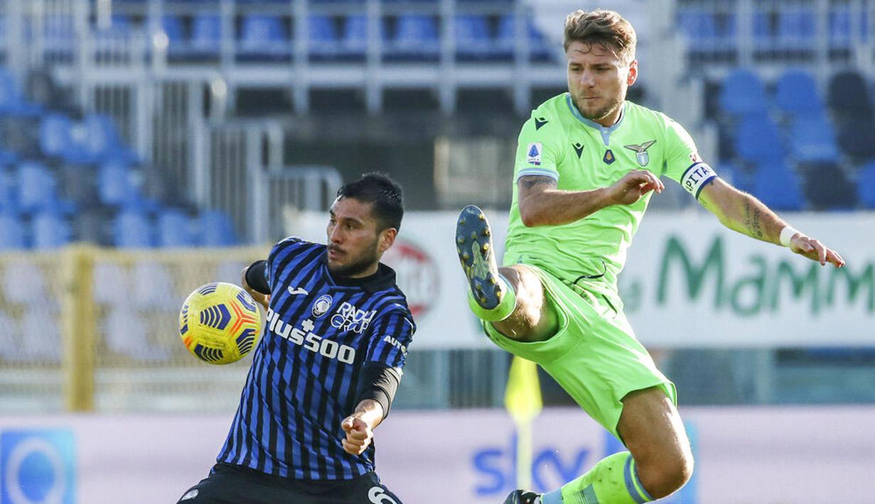 Striker Lazio, Ciro Immobile, berebut bola dengan pemain Atalanta, José Luis Palomino, pada laga Liga Italia di Stadion Gewiss, Minggu (31/1/2021). Lazio menang dengan skor 3-1. (Stefano Nicoli/LaPresse via AP)