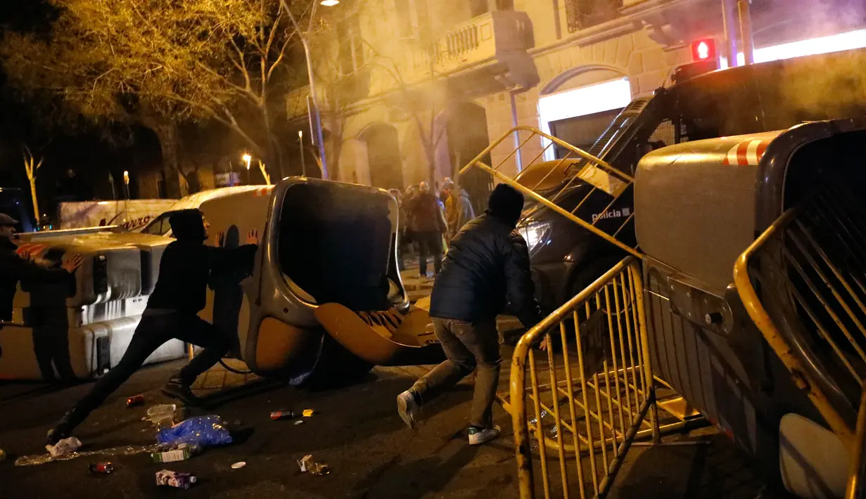 Demonstran pro kemerdekaan Catalonia merusak tempat sampah dan besi pembatas di Barcelona, Spanyol, Minggu (25/3). Demonstran memprotes penangkapan mantan pemimpin ekstrem Catalonia, Carles Puigdemont. (Foto AP/Emilio Morenatti)