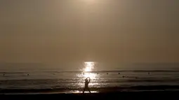 Seorang pria melakukan pemanasan sebelum berselancar di sebuah pantai di La Serena, Chile, Selasa (23/5/2015). (REUTERS/Marcos Brindicci)