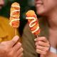 Dua orang sedang menunjukkan kuliner kekinian corndog sosis (Sumber: Freepik)