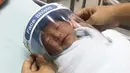 Perawat menyesuaikan pelindung wajah mungil untuk bayi yang baru lahir di Rumah Sakit Paolo Samutprakarn, Provinsi Samutprakarn, Thailand, Jumat (3/4/2020). Langkah ini dilakukan untuk mencegah penularan virus corona COVID-19 pada bayi-bayi yang baru lahir. (Paolo Hospital Samutprakarn via AP)