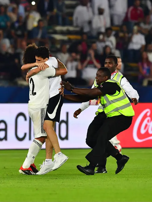 Seorang fans memeluk bek Real Madrid, Marcelo selama pertandingan semifinal Piala Dunia Antarklub 2018 antara Real Madrid melawan Kashima Antlers di stadion Zayed Sports City di Abu Dhabi, Uni Emirat Arab (19/12). (AFP Photo/Giuseppe Cacace)