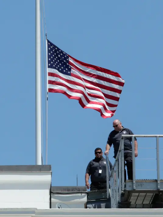 Petugas seusai menurunkan bendera setengah tiang di Gedung Putih, Washington DC, sebagai tanda berduka atas penembakan brutal klub gay Pulse di Kota Orlando, Florida, Amerika Serikat (AS), Minggu (12/6). (AFP PHOTO/Yuri GRIPAS)