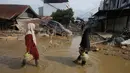 Hingga Kamis (5/12/2025) malam, listrik belum menyala, sehingga jalanan masih gelap gulita. Tampak dalam foto, para penyintas berjalan melewati reruntuhan mobil di area terdampak banjir bandang di Aceh Tamiang, Sumatera, Indonesia, Kamis 4 Desember 2025. (AP Photo/Binsar Bakkara)