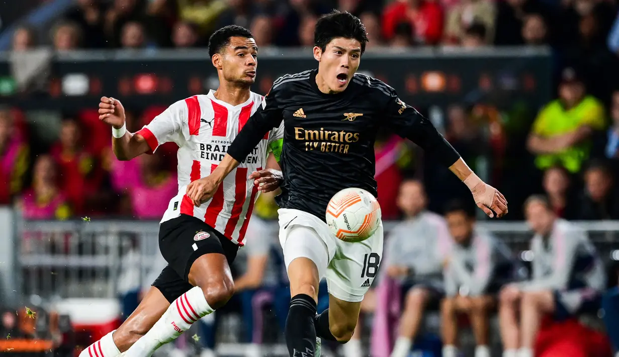Bek Arsenal, Takehiro Tomiyasu menguasai bola dibayangi striker PSV, Cody Gakpo dalam laga Grup A Liga Europa 2022/2023 di Phillips Stadium, Eindhoven (27/10/2022). Pemain yang sejak awal musim 2021/2022 menjadi milik Arsenal ini kini memiliki nilai pasar senilai 25 juta euro atau setara Rp407 miliar. (AFP/ANP/Olaf Kraak)