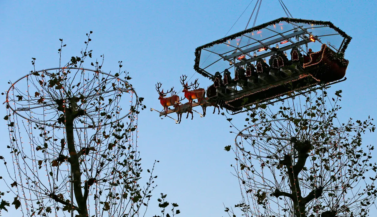 Tempat makan malam "Santa in the sky", yang diangkat dengan crane dan dihias menyerupai "Santa Sleigh" di Brussels, Belgia, 25 November 2016. Tempat makan malam ini didekorasi seperti kereta Santa Claus menjelang perayaan Natal. (REUTERS/Yves Herman)