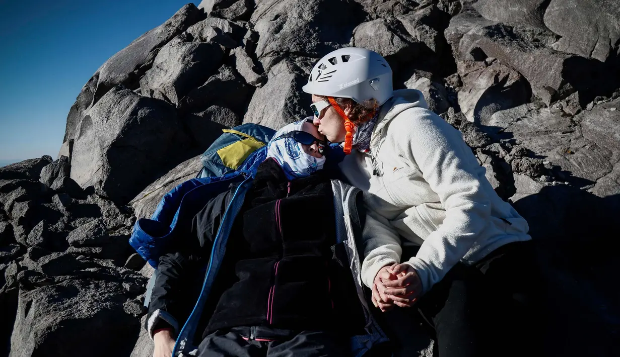 Penyintas kanker Carla Boheme (kiri) dicium oleh saudara perempuannya, Marie Boheme saat mendaki gunung berapi Pico de Orizaba dalam sebuah ekspedisi di Puebla, Meksiko, pada tanggal 24 November 2023. (Rodrigo Oropeza/AFP)