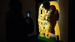 Seseorang mengambil gambar patung "Klimt kiss" yang terbuat dari susunan balok lego pada pameran Art of the Brick di Turin, Italia, Kamis (15/11). Pameran tersebut menampilkan berbagai patung lego karya seniman AS, Nathan Sawaya. (MARCO BERTORELLO/AFP)