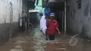 Warga melintasi banjir yang merendam Kampung Pulo, Jatinegara, Jakarta Timur, Selasa (10/2/2015). Sebagian wilayah Jakarta terendam banjir akibat hujan yang terus turun sejak Minggu (8/2) malam lalu. (Liputan6.com/Herman Zakharia)