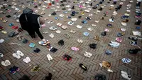 Seorang perempuan menempatkan sepasang sepatu di antara ribuan sepatu lainnya untuk melambangkan anak-anak yang tewas di Gaza selama perang antara Israel dan Hamas, di De Binnenrotte di Rotterdam pada 20 Desember 2023. (ROBIN UTRECHT / ANP / AFP)