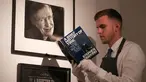 Asisten galeri berpose dengan salinan buku “A History of Time” yang ditandatangani dengan cap jempol oleh fisikawan Stephen Hawking selama sesi pemotretan untuk acara pelelangan di Balai Lelang Christie, London, Selasa (30/10). (Daniel LEAL-OLIVAS/AFP)