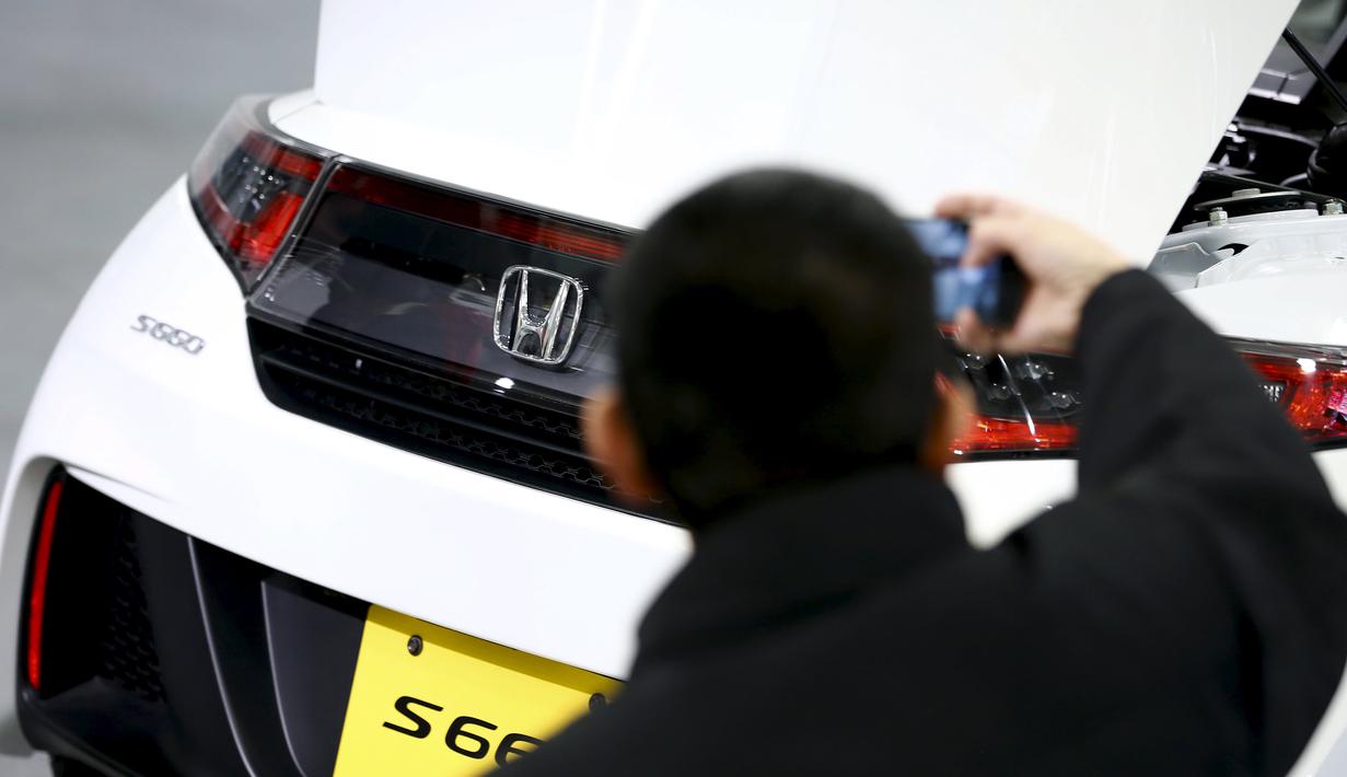 Pengunjung mengambil gambar bagian belakang mobil Honda S660 di markas besar Honda Motor Co di Tokyo, Jepang, (24/2). Mobil berbobot kira-kira 830kg dengan transmisi manual dan 850kg dengan CVT otomatis. (REUTERS/Thomas Peter)