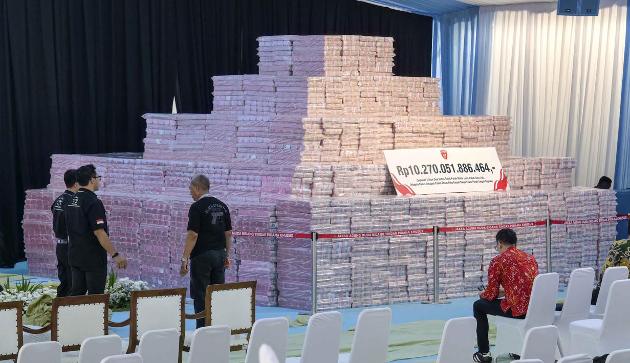 Penyerahan tahap VII ini bakal disaksikan langsung Presiden Prabowo Subianto. Tampak dalam foto, para pejabat menyiapkan tumpukan duit kertas rupiah senilai sekitar 586,8 juta USD, nan disita dari beragam kasus korupsi dan denda lingkungan, sebelum upacara penyerahan dari Kejaksaan Agung kepada pemerintah Indonesia di gedung Kejaksaan Agung di Jakarta pada Rabu 13 Mei 2026. (BAY ISMOYO/AFP)