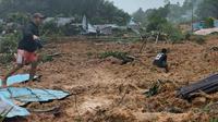 Foto selebaran yang diambil dan dirilis pada 6 Maret 2023 oleh BNPB (Badan Nasional Penanggulangan Bencana) ini menunjukkan orang-orang memeriksa kerusakan di sebuah desa yang dilanda tanah longsor di Natuna, Kepulauan Riau (Kepri) pada 6 Maret 2023.  (Photo by BNPB / AFP)