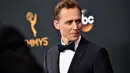 Mengenakan Tuksedo hitam dengan dasi kupu-kupu, Tom Hiddleston juga menjadi salah satu nominasi di Emmy Awards kategori Outstanding Lead Actor for Mini Series or A Movie untuk TV Series. (AFP/Bintang.com)