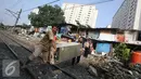 Warga membawa barang berharga saat alat berat merobohkan bangunan di kawasam Rawajati, Jakarta, Kamis (1/9). Penertiban tersebut menyebabkan warga terpaksa menyelamatkan barang berharga mereka ke tepi rel kereta api. (Liputan6.com/Immanuel Antonius)