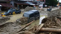 Mobil-mobil terjebak lumpur di daerah yang terkena banjir bandang di Masamba, Sulawesi Selatan, Rabu (15/7/2020). Banjir bandang akibat tingginya curah hujan tersebut mengakibatkan 16 orang meninggal dunia dan puluhan warga dilaporkan masih dalam pencarian. (AP/Khaizuran Muchtamir)