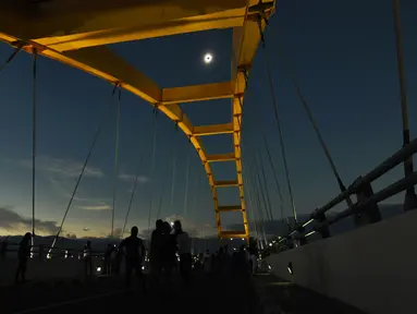 Warga menyaksikan fase puncak Gerhana Matahari Total (GMT) yang dilihat dari Jembatan Teluk Palu, Sulawesi Tengah, Rabu (9/3/2015). (Nanang/AFP)
