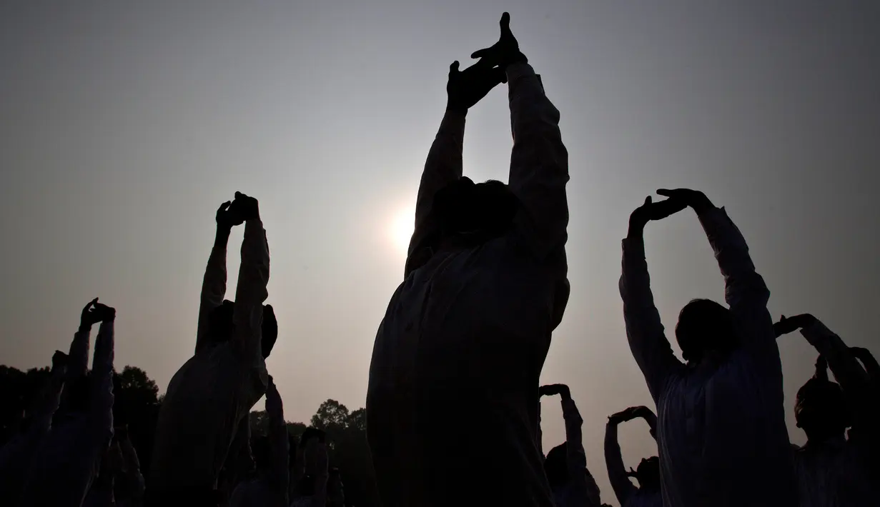 Siluet anggota nasionalis Hindu Rashtriya Swayamsevak Sangh (RSS) saat mengikuti yoga massal di Gauhati, India (21/1). Menurut seorang pejabat RSS, yoga massal ini diikuti lebih dari tiga puluh ribu sukarelawan. (AP Photo / Anupam Nath)