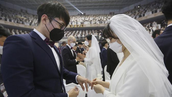 Pengantin wanita mamasangkan cincin ke jari pasangannya selama mengikuti pernikahan massal di Cheong Shim Peace World Center, Gapyeong, Korea Selatan, Jumat, (7/2/2020). Kegiatan pernikahan massal ini digelar setiap tahun dan diikuti juga oleh pasangan asing. (AP Photo/Ahn Young-joon)