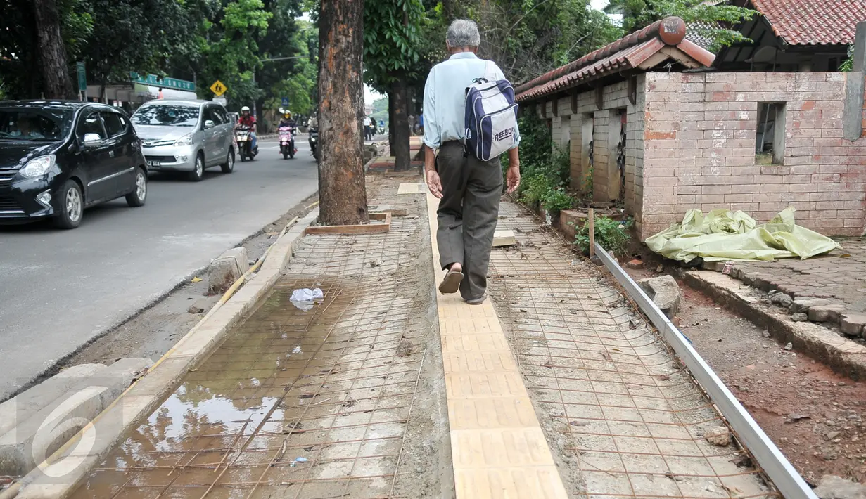 Pejalan kaki melintasi jalur pembangunan trotoar di Jalan Raya Ragunan, Jakarta, Rabu (12/10). Suku Dinas Bina Marga Jaksel mengalokasikan anggaran Rp 79 miliar untuk pembangunan dan perbaikan trotoar di 10 kecamatan Jaksel. (Liputan6.com/Yoppy Renato)