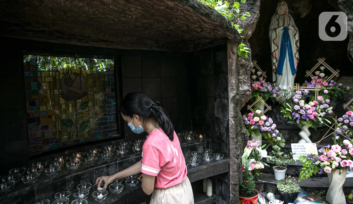 Seorang wanita bermasker meletakkan lilin pada wadah kaca selama masa pandemi virus corona COVID-19 di Gereja Theresia, Jakarta, Minggu (20/12/2020). Dekorasi bernuansa pandemi COVID-19 dan kesederhanaan disiapkan untuk memeriahkan perayaan Natal tahun ini. (Liputan6.com/Faizal Fanani)