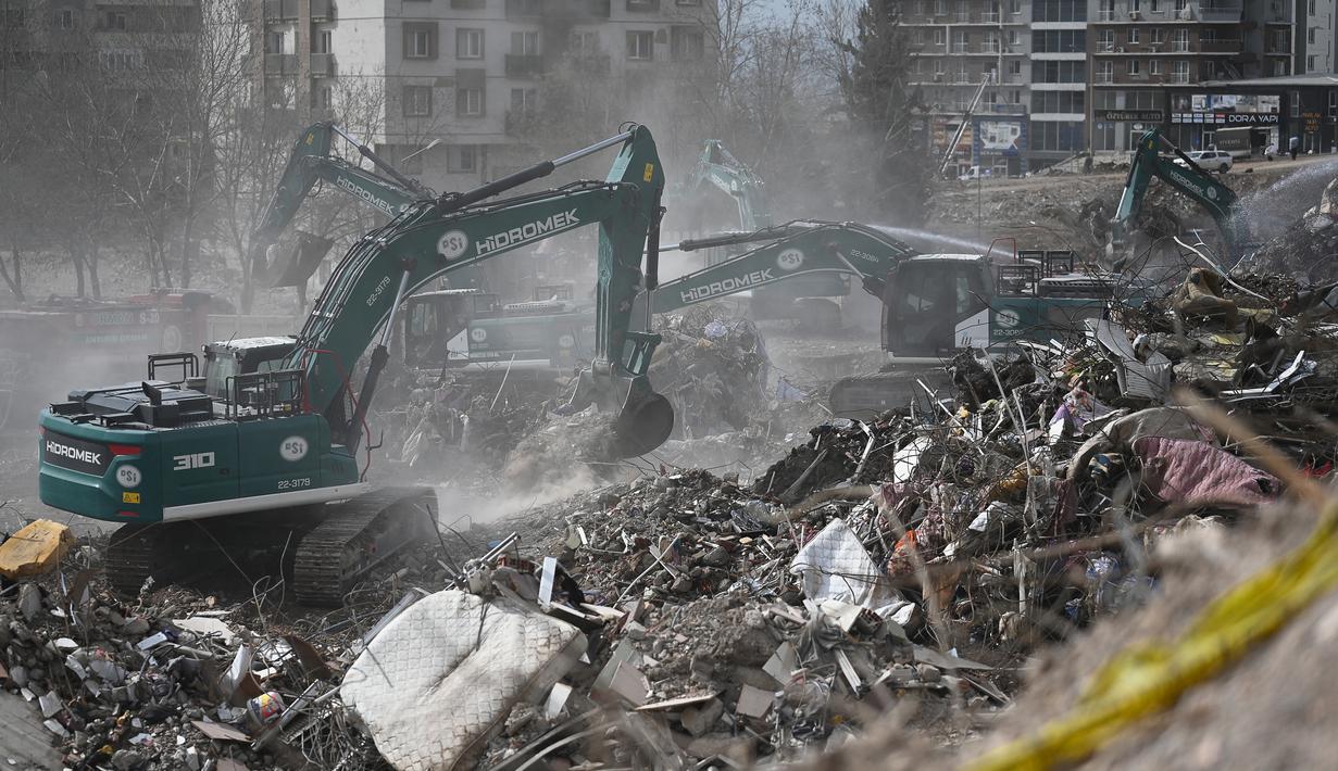 Para pekerja mengoperasikan alat berat saat membersihkan puing-puing dari gedung Ebrar yang runtuh satu bulan setelah gempa besar melanda Turki tenggara di Kahramanmaras, pada 4 Maret 2023. Gempa bumi besar berkekuatan 7,8 mengguncang sebagian besar Turki dan sebagian Suriah pada 6 Februari 2023, menewaskan lebih dari 50.000 orang di kedua negara, dengan sekitar 46.000 di pihak Turki. (AFP/Eylul  Yasar)