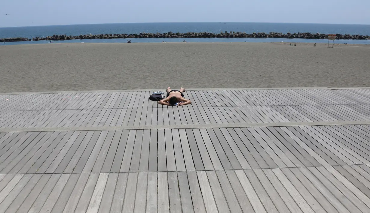 Seorang pria beristirahat di pantai Hiratsuka di Hiratsuka, prefektur Kanagawa, dekat Tokyo, Senin (8/6/2020). Jepang mengangkat keadaan darurat coronavirus-nya, mengakhiri pembatasan secara nasional ketika bisnis mulai dibuka kembali. (AP Photo/Koji Sasahara)