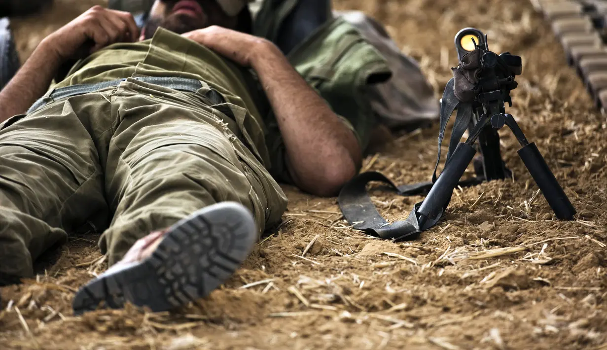 Seorang tentara Israel tidur sebelah senjatanya di luar Jalur Gaza.  (15/7/14) (REUTERS / Nir Elias)