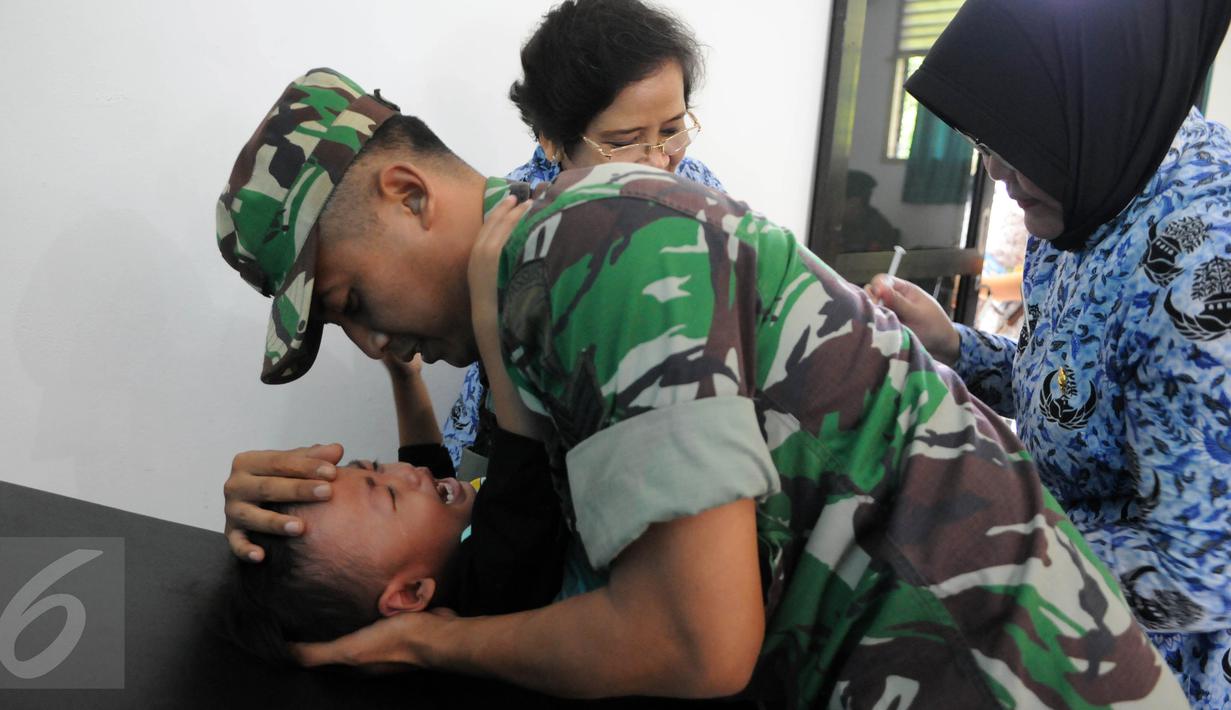 Seorang anggota TNI menenangkan anaknya yang diberi vaksin di Kantor Kesehatan Kopassus, Jakarta, Senin (18/7). Kopassus menggelar pelaksanaan vaksinasi ulang terhadap anak prajurit yang terindikasi menjadi korban vaksin palsu. (Liputan6.com/Helmi Afandi)