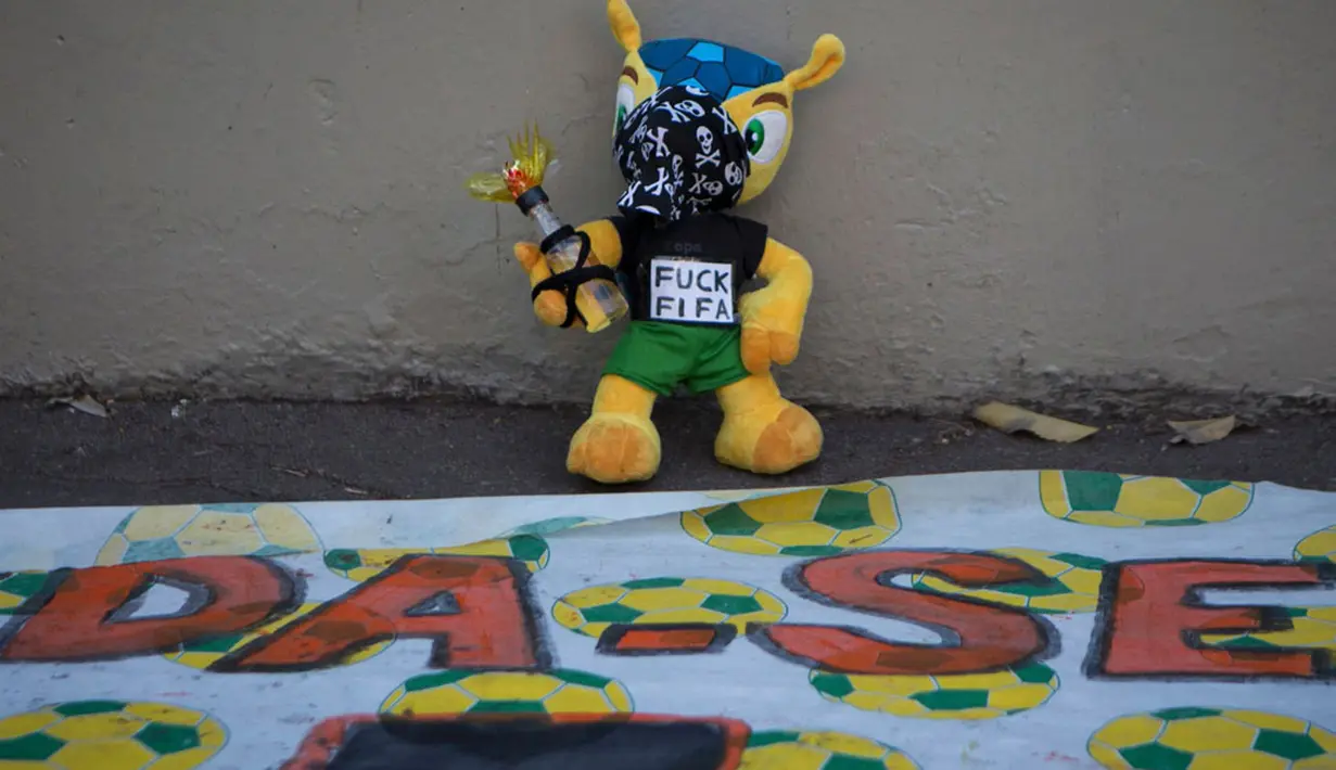 Sebuah boneka Fuleco Armadillo (maskot resmi Piala Dunia 2014) dihias menyerupai demonstran yang melakukan aksi unjuk rasa di Rio de Janeiro, Brasil, (15/6/2014). (REUTERS/Marco Bello)