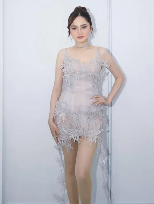 Syifa Hadju mengenakan mini dress abu-abu silver. Dress sleeveless tersebut semakin indah dengan aksen kupu-kupu yang menjuntai di bagian rok dan aksen kupu-kupu berkilau di bagian dada.  [@krinouofficial]
