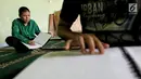 Dua santri penyandang tunanetra membaca Al Quran Braille di Yayasan Raudlatul Makfufin, Tangerang Selatan, Kamis (24/5). Yayasan yang berdiri sejak tahun 1983 ini memproduksi Al Quran Braille sebanyak 60 buku setiap harinya. (Liputan6.com/Fery Pradolo)